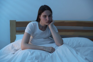 Photo of Frustrated young woman suffering from insomnia on bed indoors