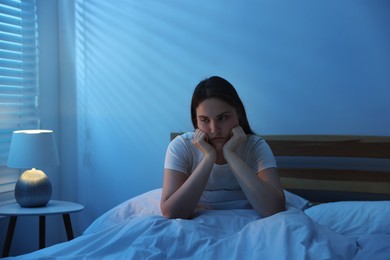 Photo of Frustrated young woman suffering from insomnia on bed indoors