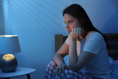 Photo of Frustrated young woman suffering from insomnia on bed indoors