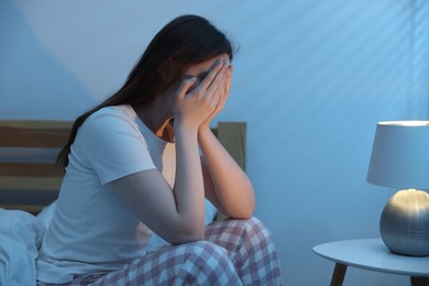 Photo of Frustrated young woman suffering from insomnia on bed indoors