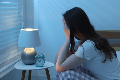 Photo of Frustrated young woman suffering from insomnia on bed indoors