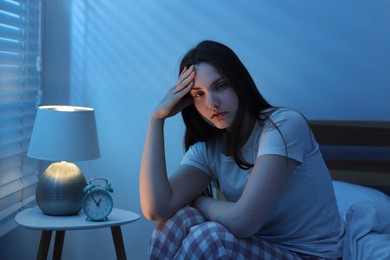 Photo of Frustrated young woman suffering from insomnia on bed indoors