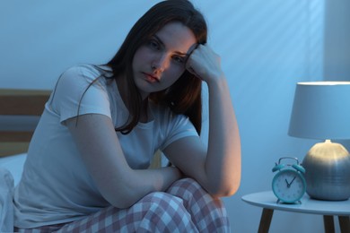Photo of Frustrated young woman suffering from insomnia on bed indoors