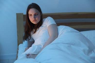 Photo of Frustrated young woman suffering from insomnia on bed indoors
