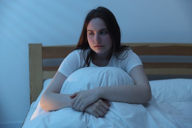 Photo of Frustrated young woman suffering from insomnia on bed indoors