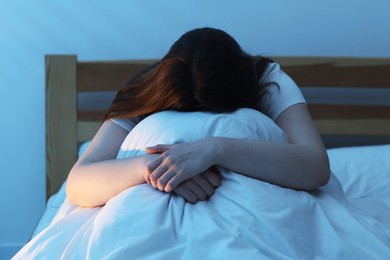 Photo of Frustrated young woman suffering from insomnia on bed indoors