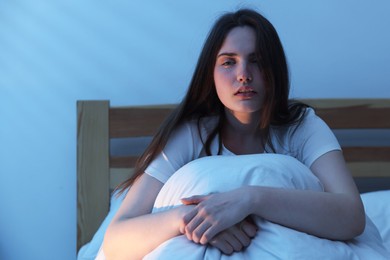 Photo of Frustrated young woman suffering from insomnia on bed indoors