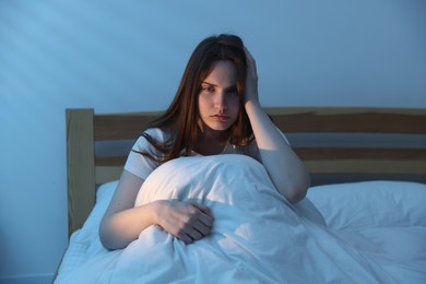 Photo of Frustrated young woman suffering from insomnia on bed indoors