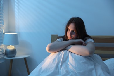 Photo of Frustrated young woman suffering from insomnia on bed indoors