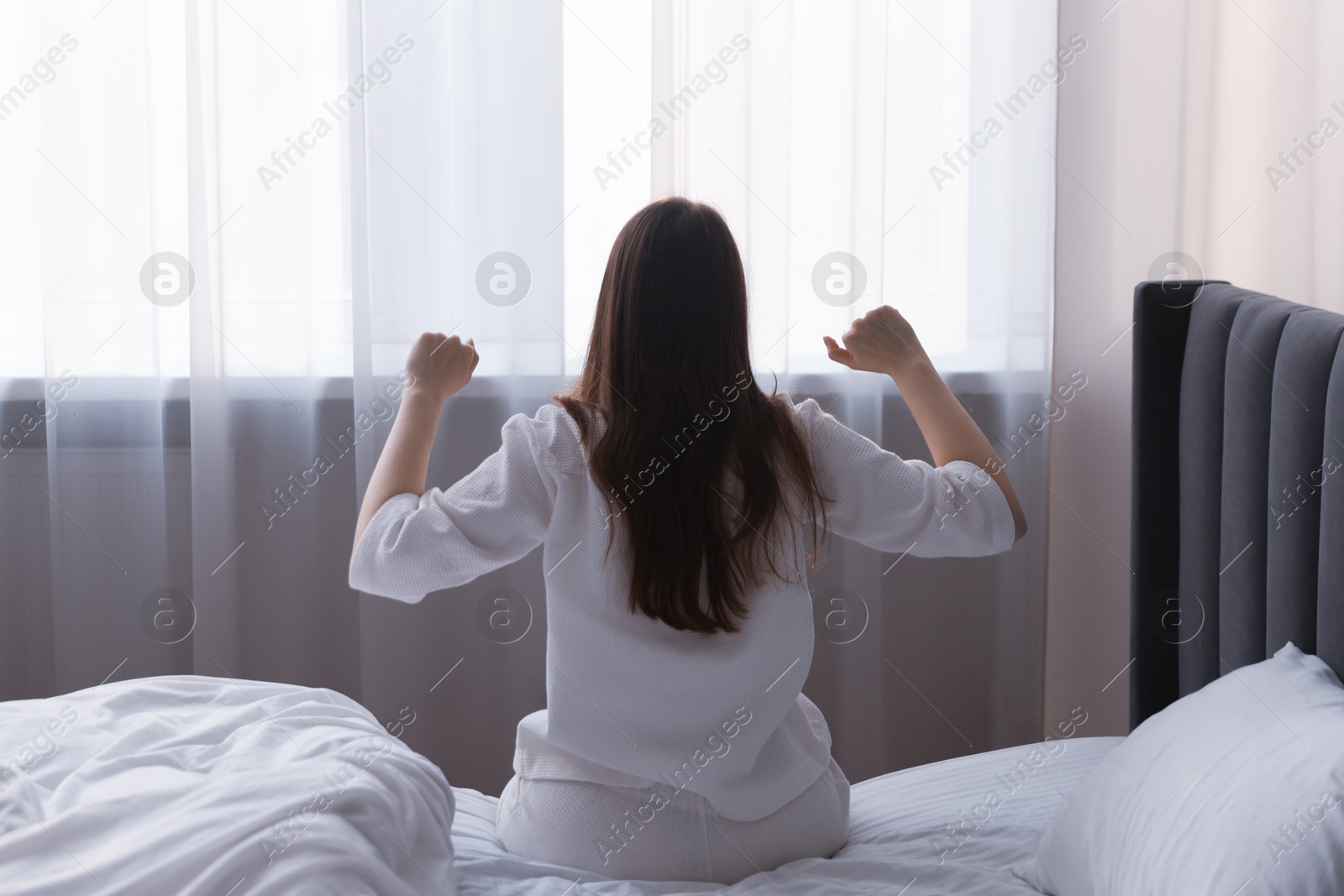 Woman stretching on bed at home, back view Photo of Woman stretching on bed at home, back view