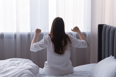 Photo of Woman stretching on bed at home, back view