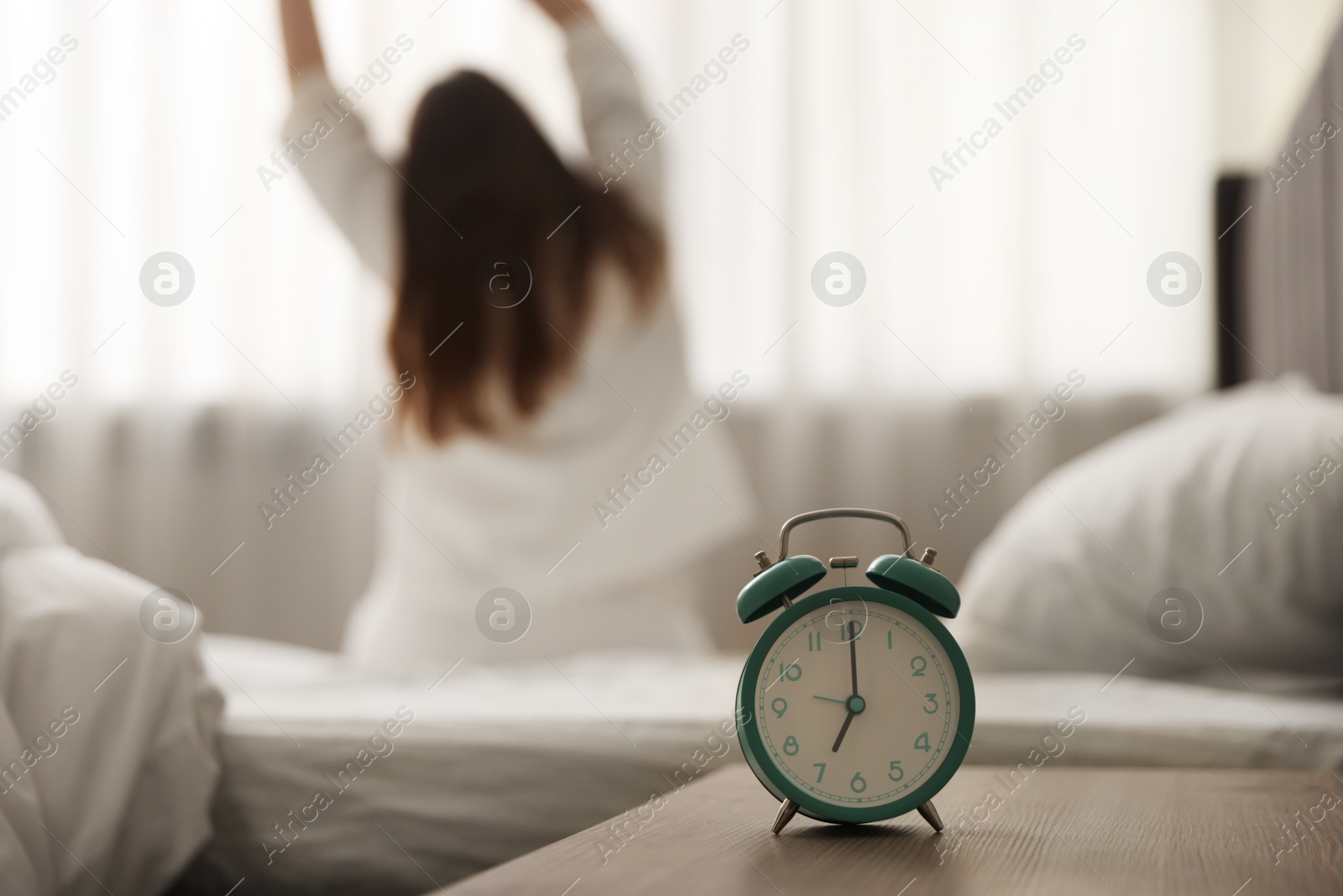 Woman stretching on bed at home, focus on alarm clock Photo of Woman stretching on bed at home, focus on alarm clock