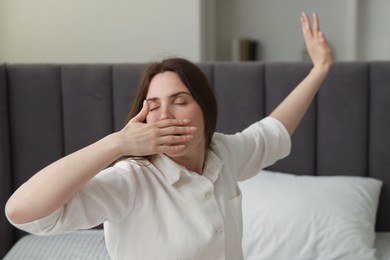 Photo of Young woman stretching on bed at home