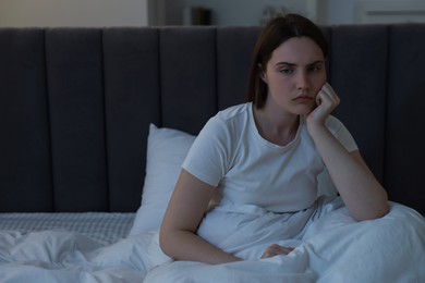 Photo of Frustrated young woman suffering from insomnia on bed indoors