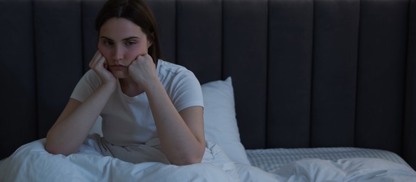 Photo of Frustrated young woman suffering from insomnia on bed indoors, space for text