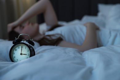 Photo of Frustrated young woman suffering from insomnia on bed indoors, selective focus