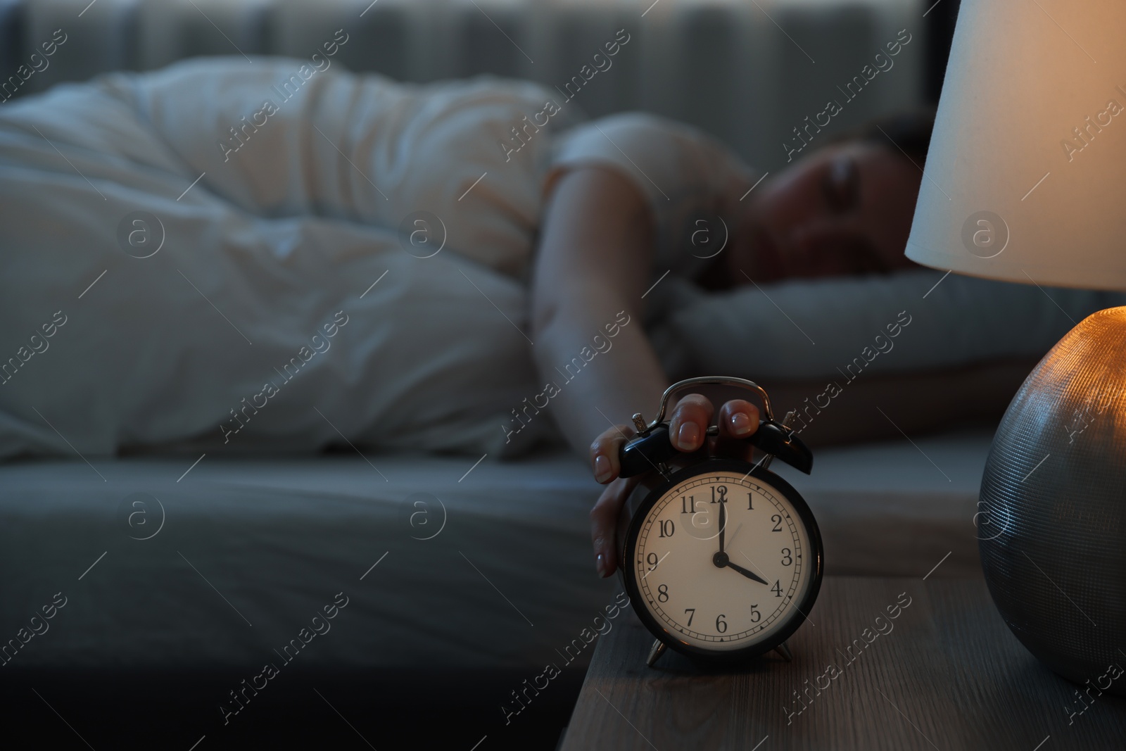 Frustrated young woman suffering from insomnia on bed indoors, focus on alarm clock Photo of Frustrated young woman suffering from insomnia on bed indoors, focus on alarm clock