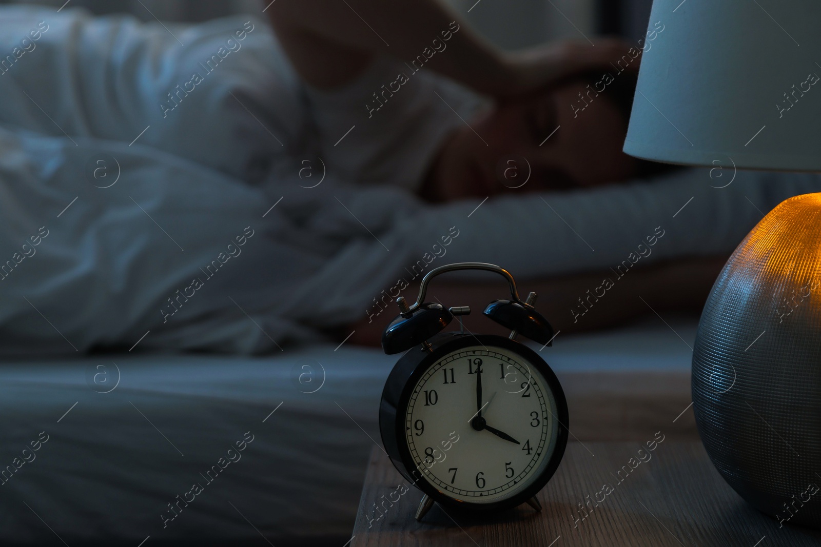 Frustrated young woman suffering from insomnia on bed indoors, focus on alarm clock Photo of Frustrated young woman suffering from insomnia on bed indoors, focus on alarm clock