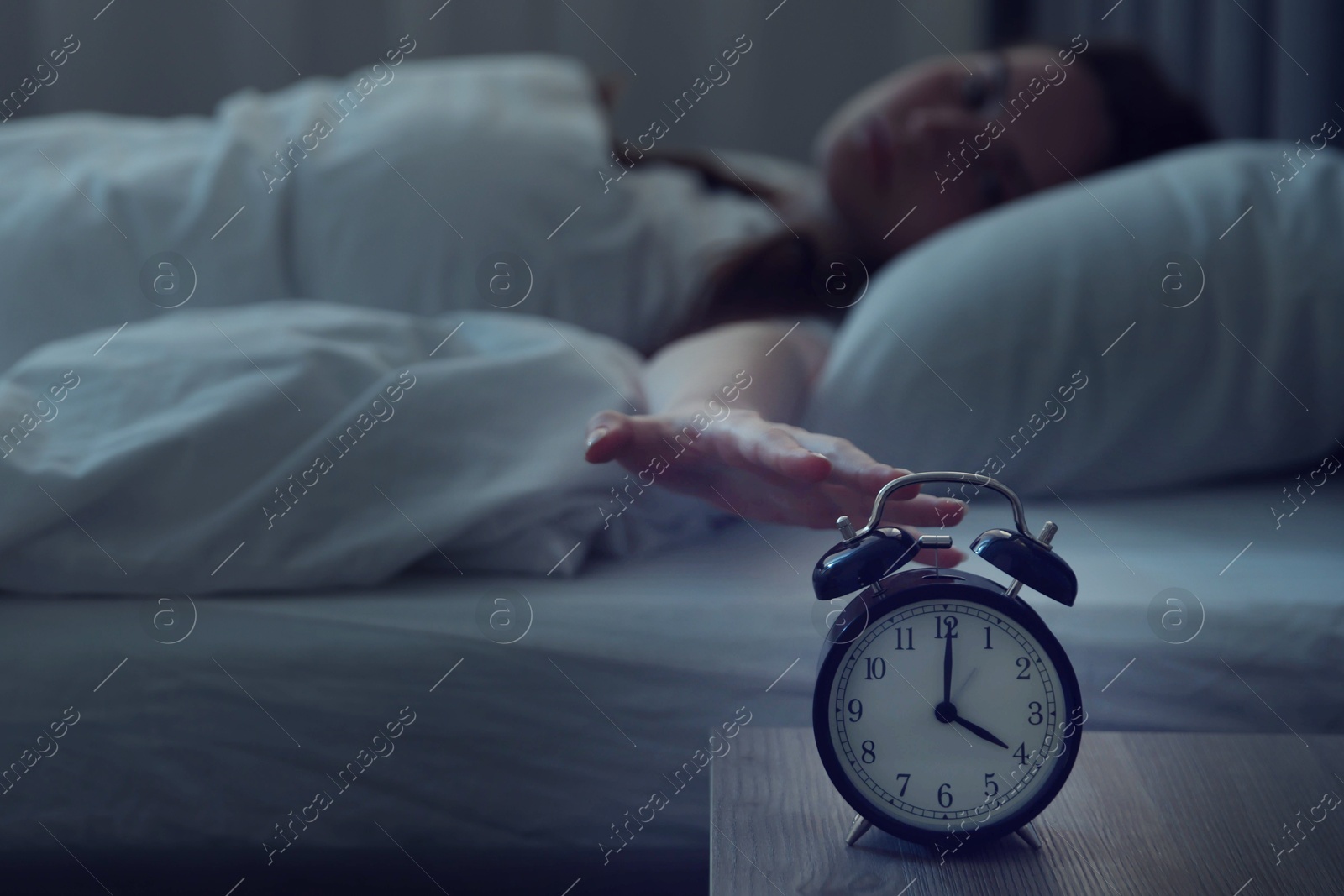 Frustrated young woman suffering from insomnia on bed indoors, focus on alarm clock Photo of Frustrated young woman suffering from insomnia on bed indoors, focus on alarm clock