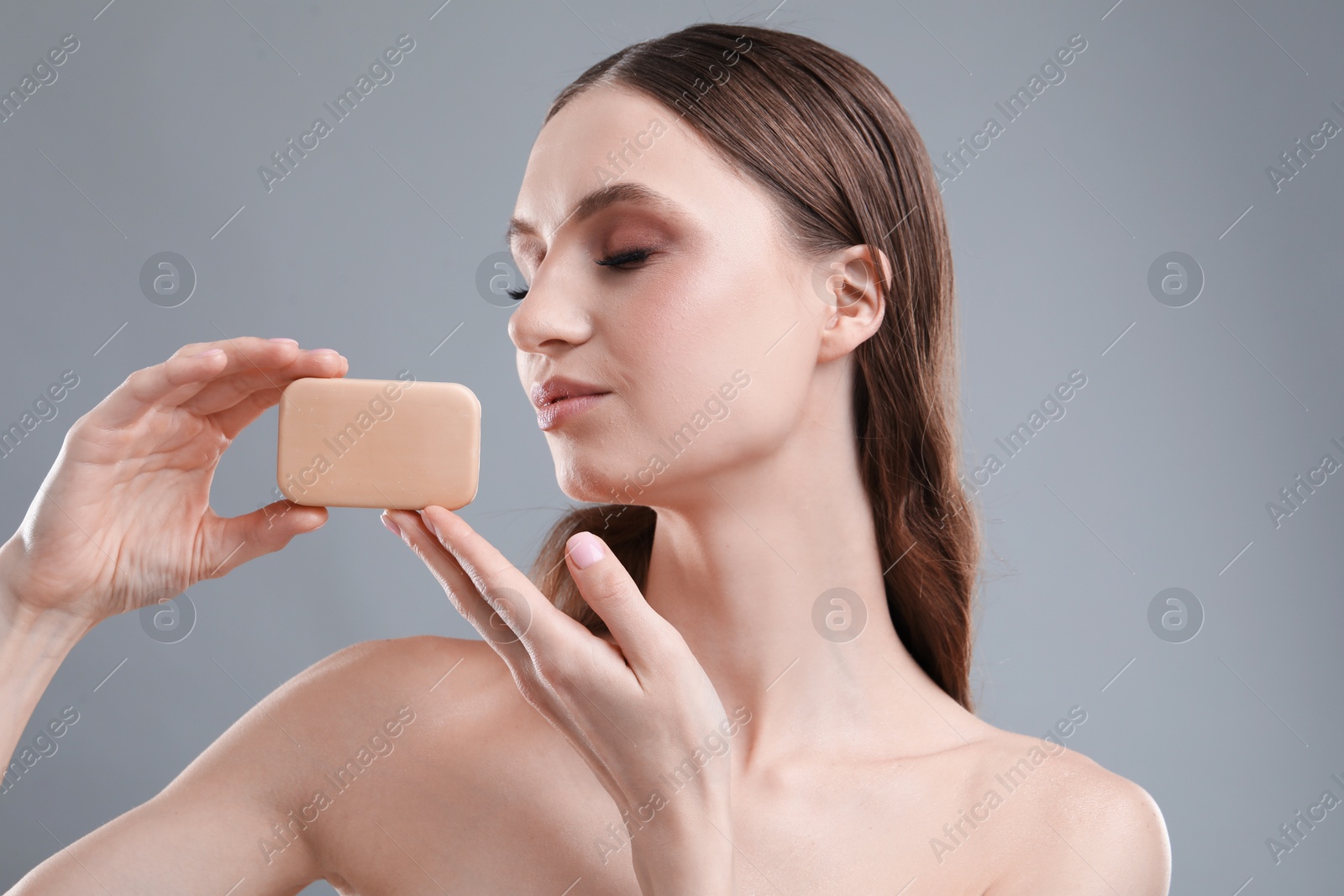 Beautiful woman with soap bar on grey background, closeup Photo of Beautiful woman with soap bar on grey background, closeup