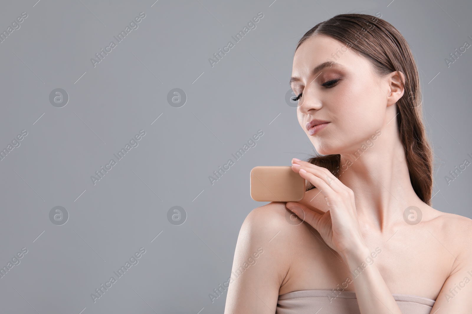 Beautiful woman with soap bar on grey background, closeup. Space for text Photo of Beautiful woman with soap bar on grey background, closeup. Space for text