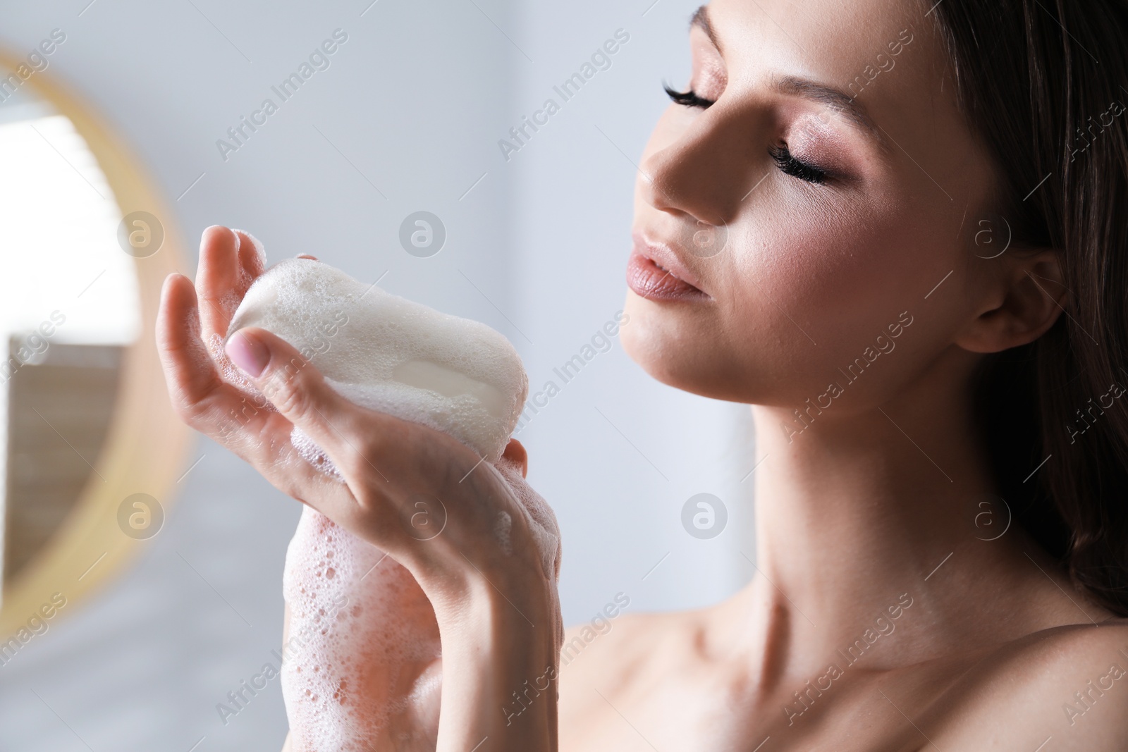 Woman with foaming soap bar in bathroom, closeup Photo of Woman with foaming soap bar in bathroom, closeup