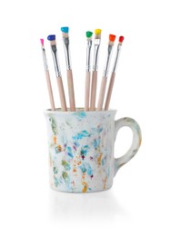 Photo of Brushes with color paints in cup isolated on white