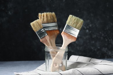 Photo of Three paintbrushes in jar on grey table