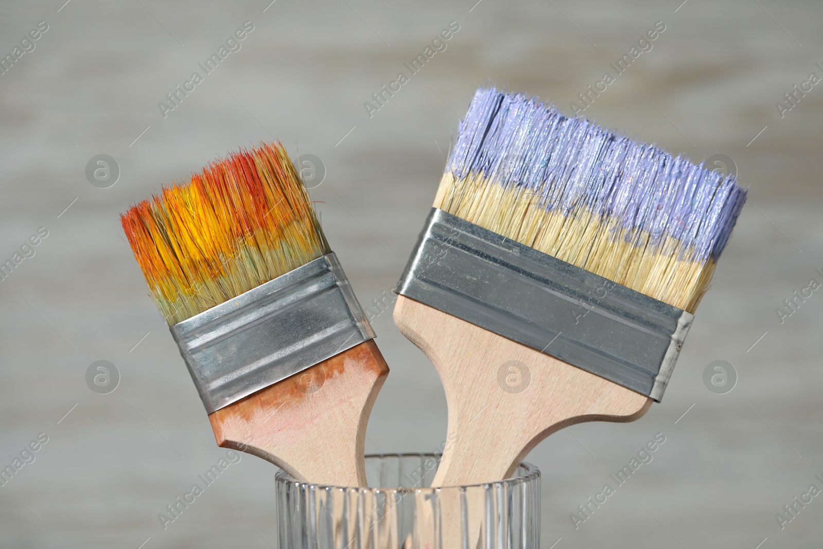 Brushes with color paints in glass on light background, closeup Photo of Brushes with color paints in glass on light background, closeup