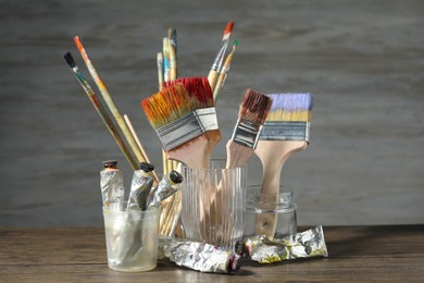 Photo of Brushes and color paints on wooden table