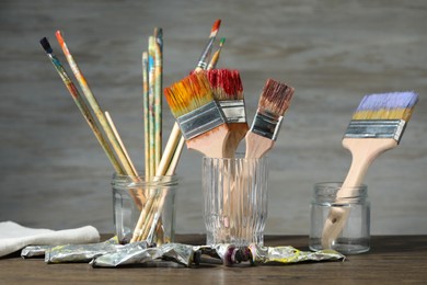 Photo of Brushes and color paints on wooden table