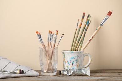Photo of Brush with color paints on wooden table