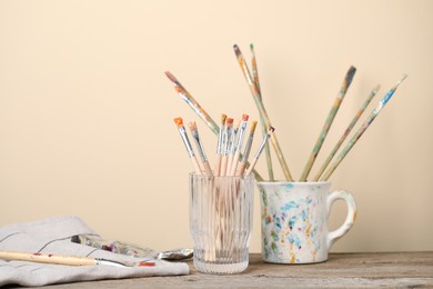 Photo of Brush with color paints on wooden table