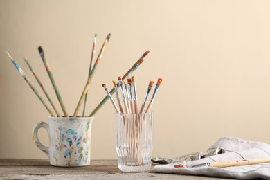 Photo of Brush with color paints on wooden table. Space for text