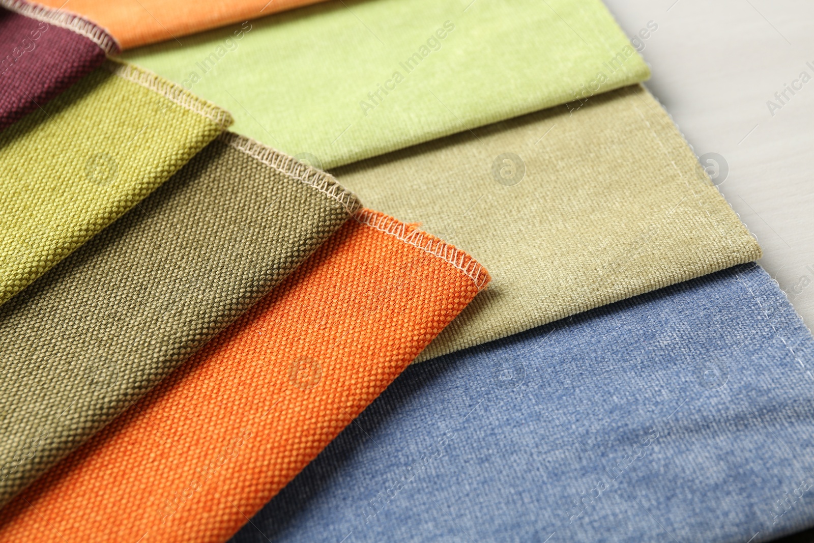 Samples of different fabrics on light wooden table, closeup Photo of Samples of different fabrics on light wooden table, closeup