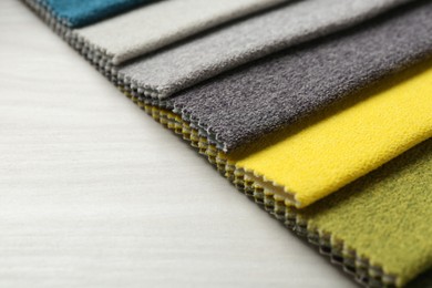 Photo of Samples of different fabrics on light wooden table, closeup. Space for text