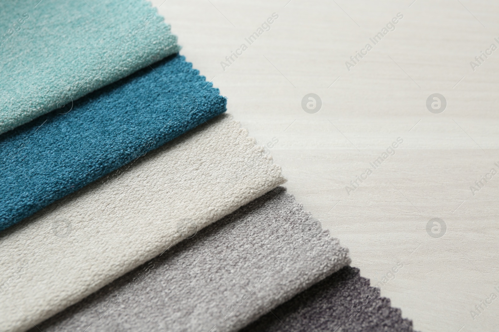 Samples of different fabrics on light wooden table, closeup. Space for text Photo of Samples of different fabrics on light wooden table, closeup. Space for text