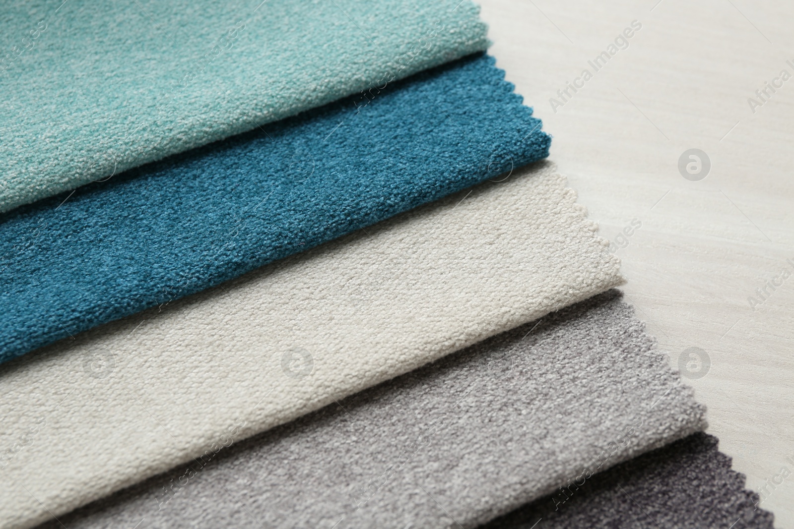Samples of different fabrics on light wooden table, closeup Photo of Samples of different fabrics on light wooden table, closeup