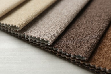 Photo of Samples of different fabrics on light wooden table, closeup