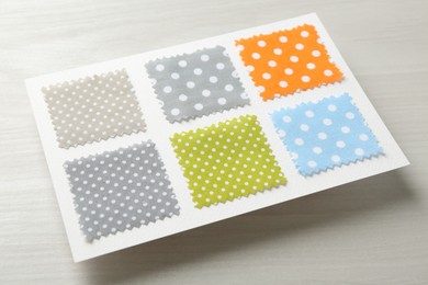 Photo of Samples of fabrics with polka dot pattern on light wooden table