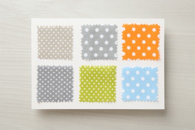 Photo of Samples of fabrics with polka dot pattern on light wooden table, top view