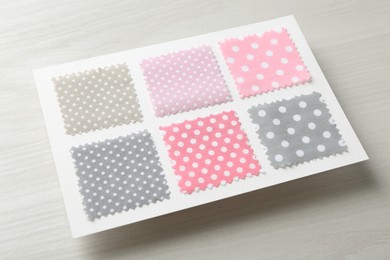 Photo of Samples of fabrics with polka dot pattern on light wooden table