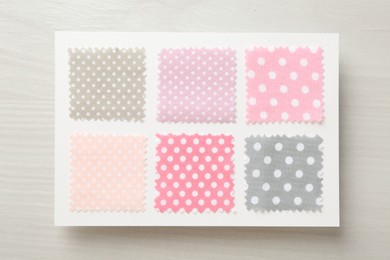 Photo of Samples of fabrics with polka dot pattern on light wooden table, top view