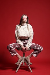 Photo of Fashionable portrait of beautiful woman in stylish outfit on red background