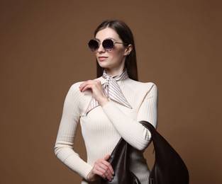 Photo of Fashionable portrait of beautiful woman in stylish outfit on brown background