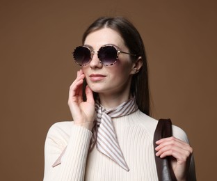 Photo of Fashionable portrait of beautiful woman in stylish outfit on brown background