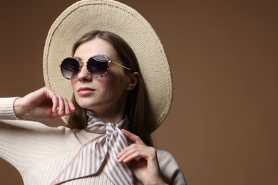 Photo of Fashionable portrait of beautiful woman in stylish outfit on brown background. Space for text