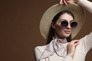 Photo of Fashionable portrait of beautiful woman in stylish outfit on brown background. Space for text