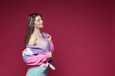 Photo of Fashionable portrait of beautiful woman in stylish outfit on crimson background. Space for text
