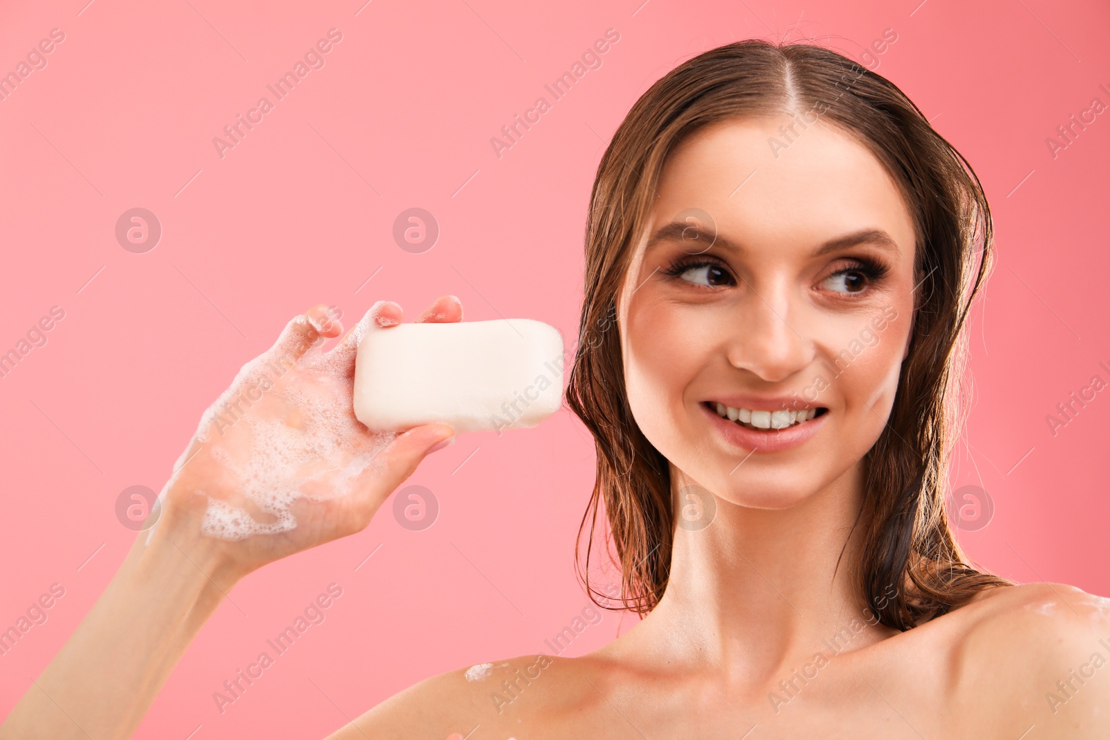 Smiling woman with foaming soap bar on pink background, closeup Photo of Smiling woman with foaming soap bar on pink background, closeup
